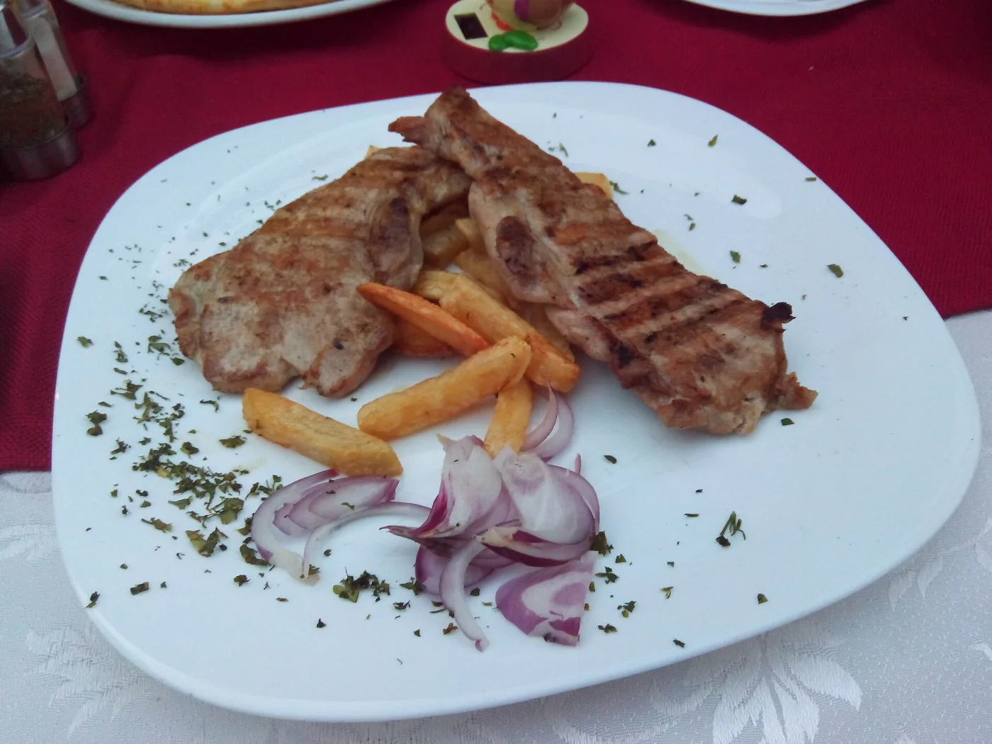 Тарелка в черногорском ресторане: мясо с гриля, картофель фри и кольца сырого лука