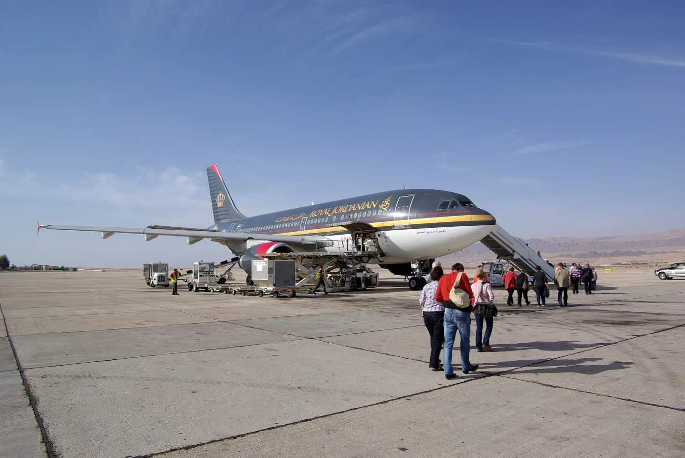 Самолёт Royal Jordanian на перроне аэропорта Акабы, пассажиры идут к трапу, на горизонте пустынные горы